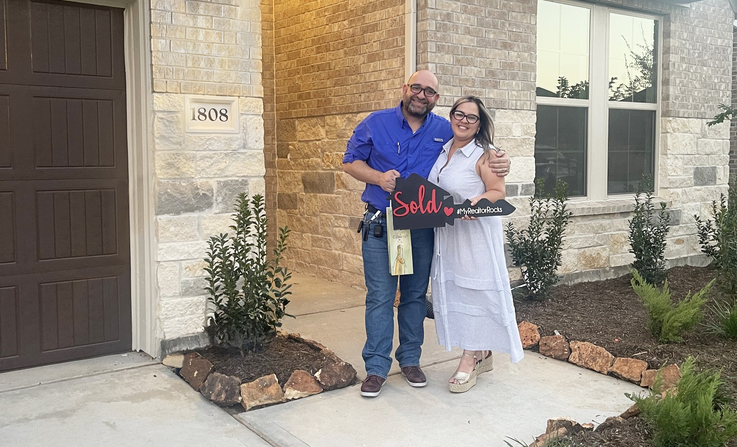 Couple posing in front of their new home after closing